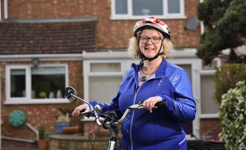 Lady in helmet holds onto handles of bike. Her cycling jacket is slightly open to show the CUE1 device placed on the centre of her chest.