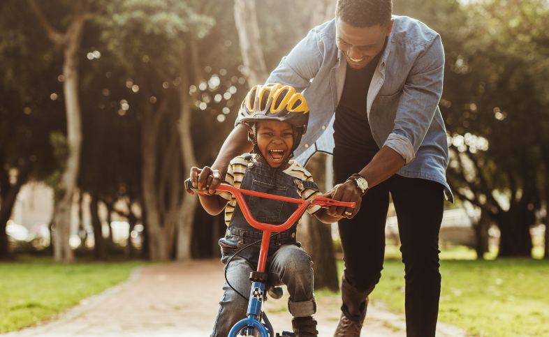 Man helps son learn to ride his bike