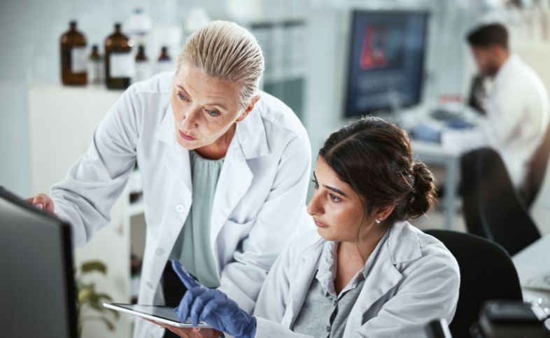 Two ladies working in a lab, wearing white lab coats
