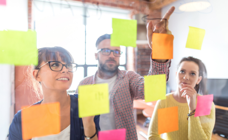 Collaborative working - group places post it notes on glass screen