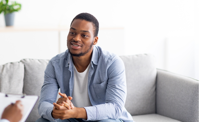 Man sits on grey sofa during therapy session