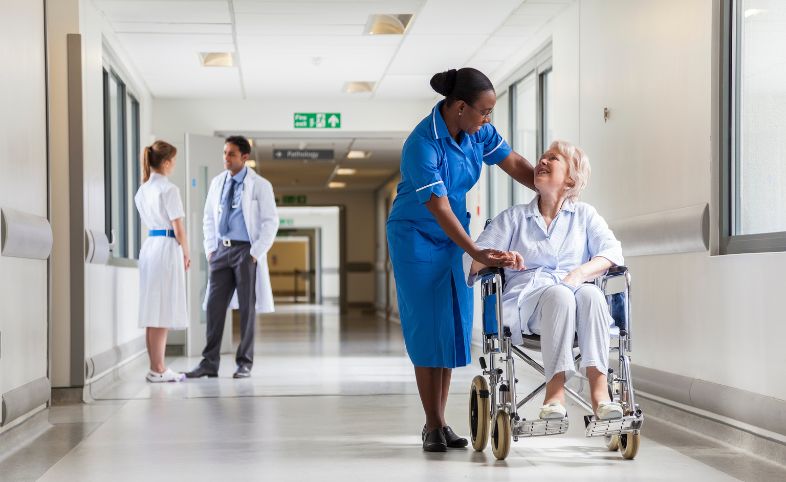 In a hospital corridor, a nurse looked down at a elderly patient in a wheelchair