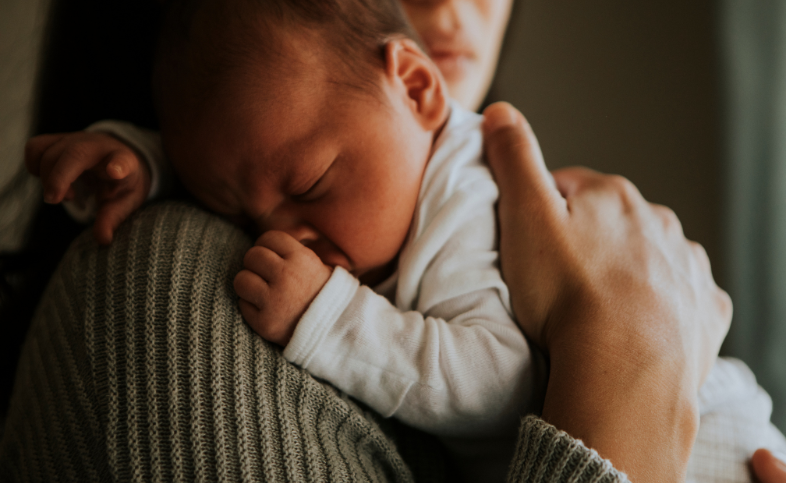 Small baby sleeping on person's shoulder