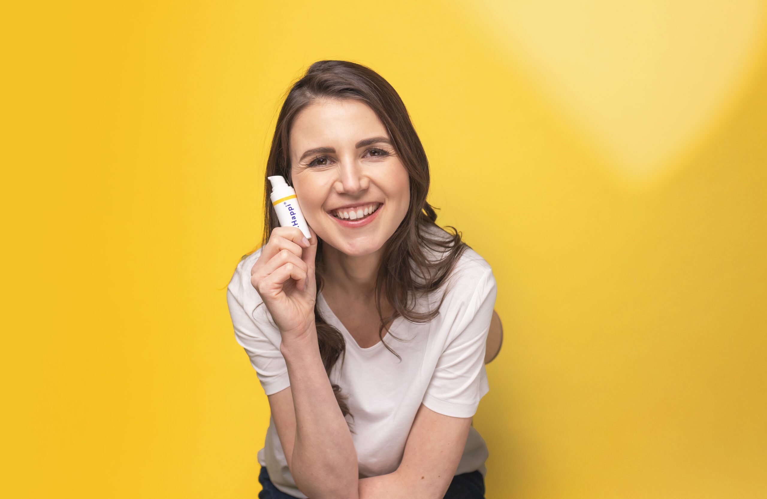 image of a woman holding a tube shaped product on a yellow background