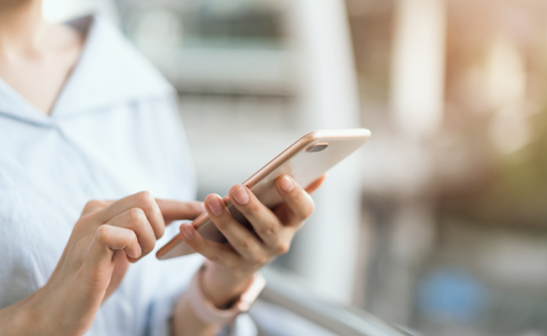 image of a phone being held by hands with a blurred background.