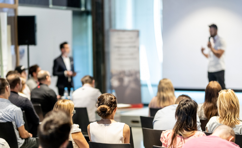 Audience of attendees listen to a presentation