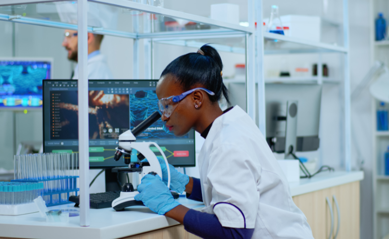 Researcher in lab looks in a microscope.