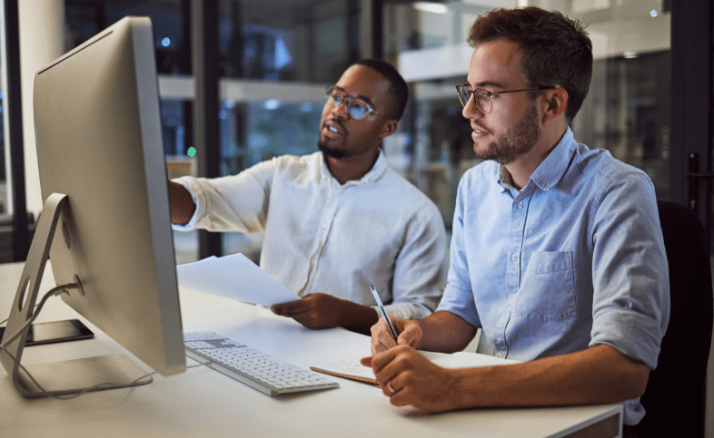 Two data scientists look at a computer screen