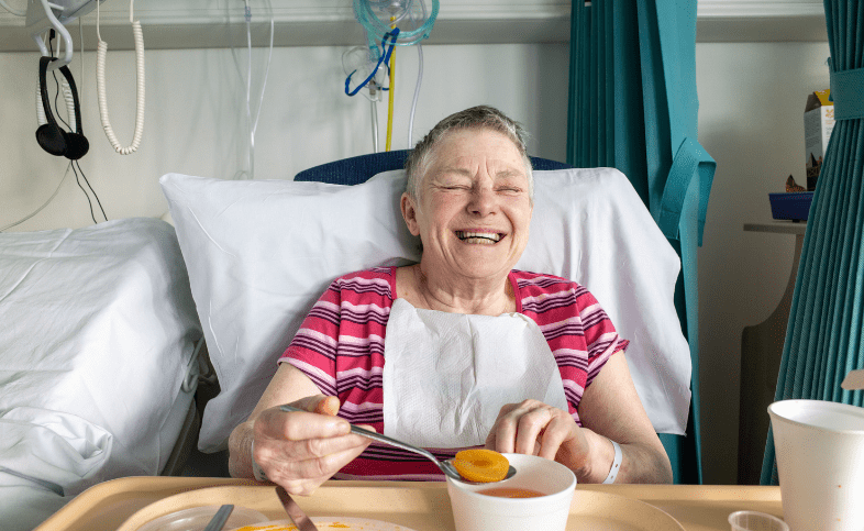 Elderly lady in hospital eats a peach in bed