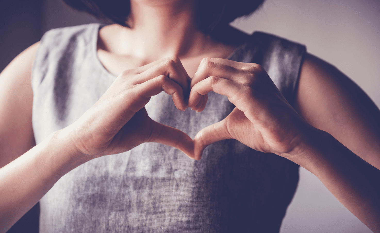 Lady holds hands in front of chest in the shape of a heart