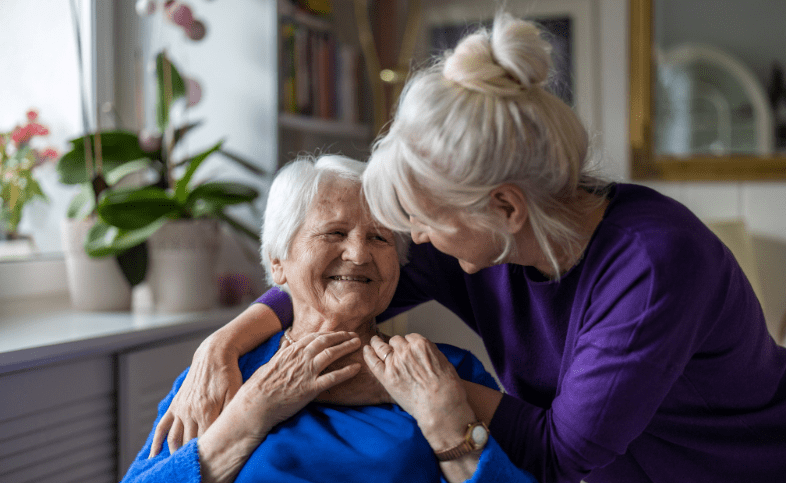 Two white haired ladies smile at one another