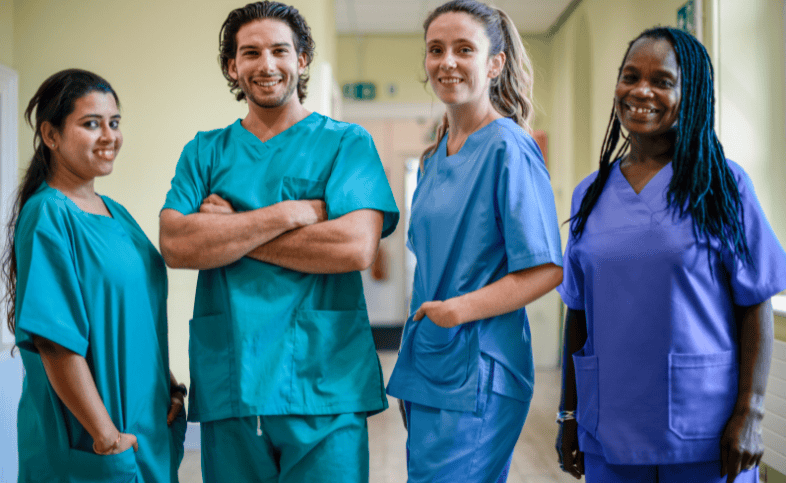 Four hospital staff stand in a line in scrubs
